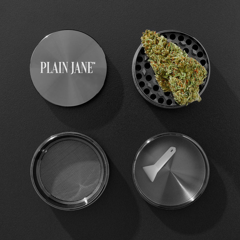 Plain Jane grinder components and photographed cannabis flower on a dark slate surface