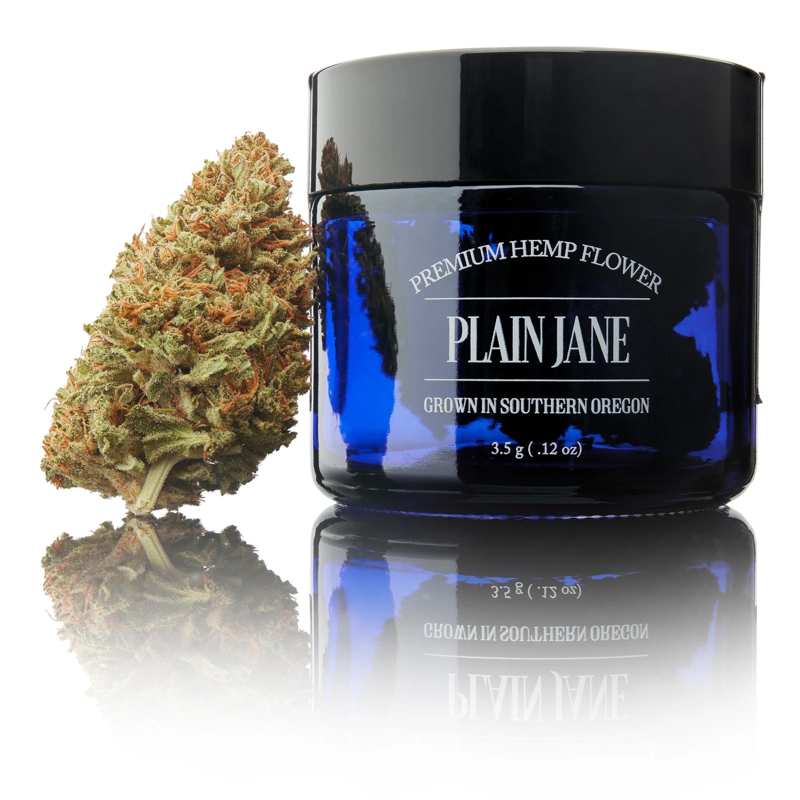 Real CBD flower beside a cobalt-blue Plain Jane jar in a white studio setting