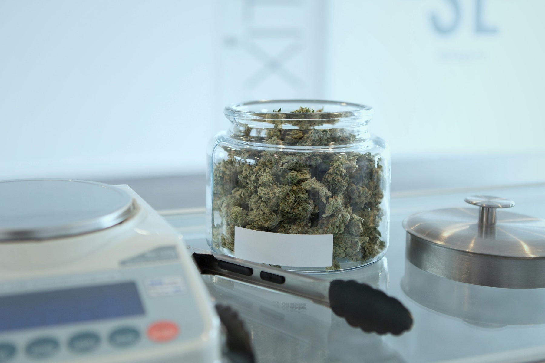 Glass jar of cannabis flower on a digital scale for a price-per-gram comparison