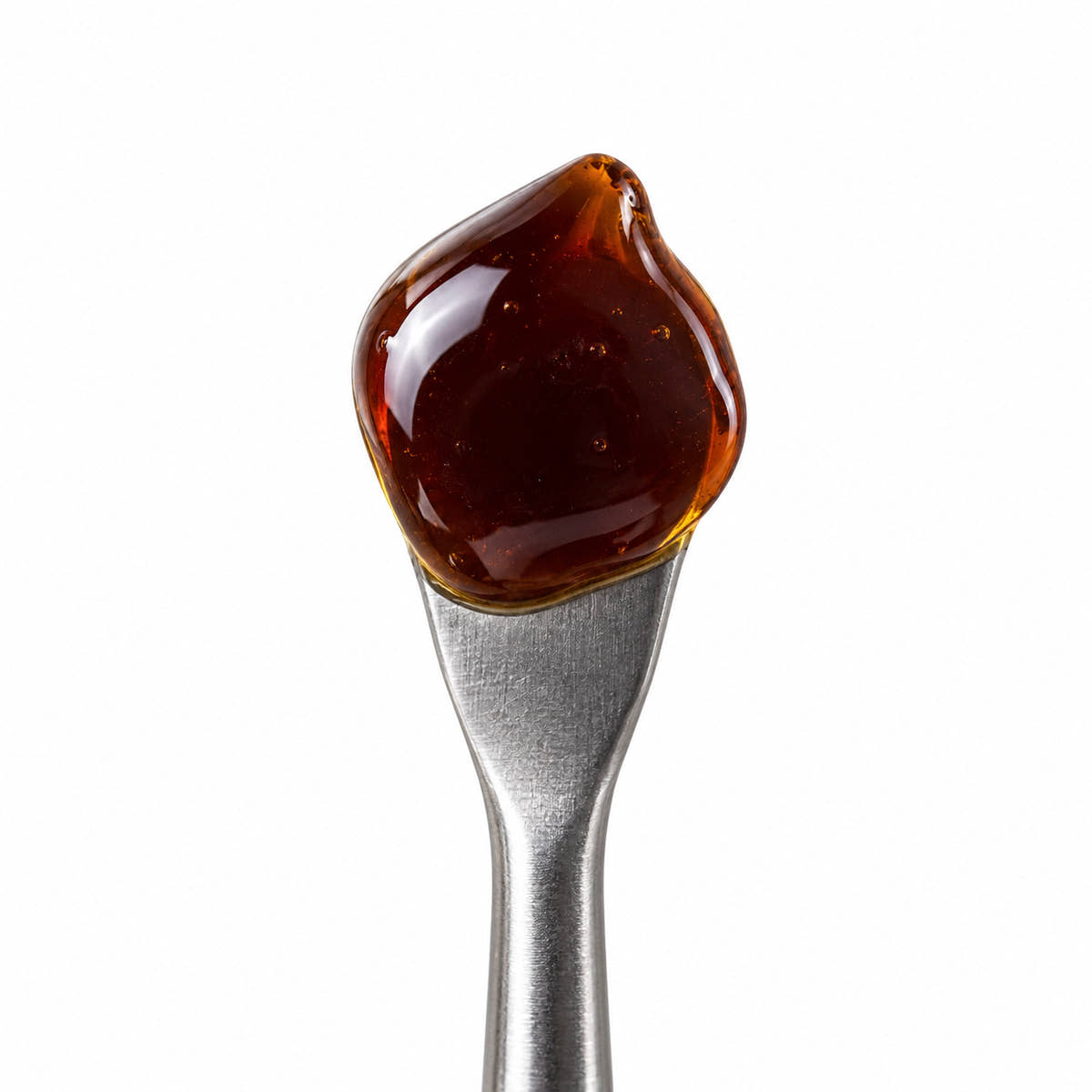 Crystal-Resistant CBD Distillate on a stainless steel concentrate tool against a clean white background