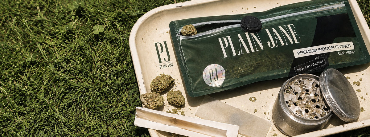 Plain Jane CBD flower pack and rolling tray on green grass