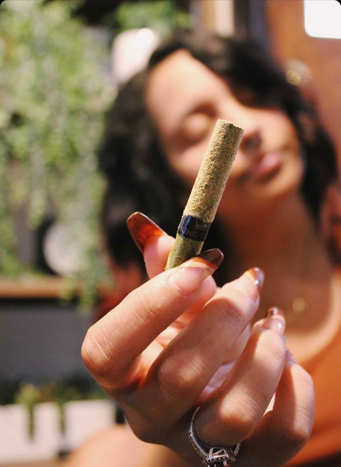 Person holding a hemp joint in a sunlit lifestyle photograph