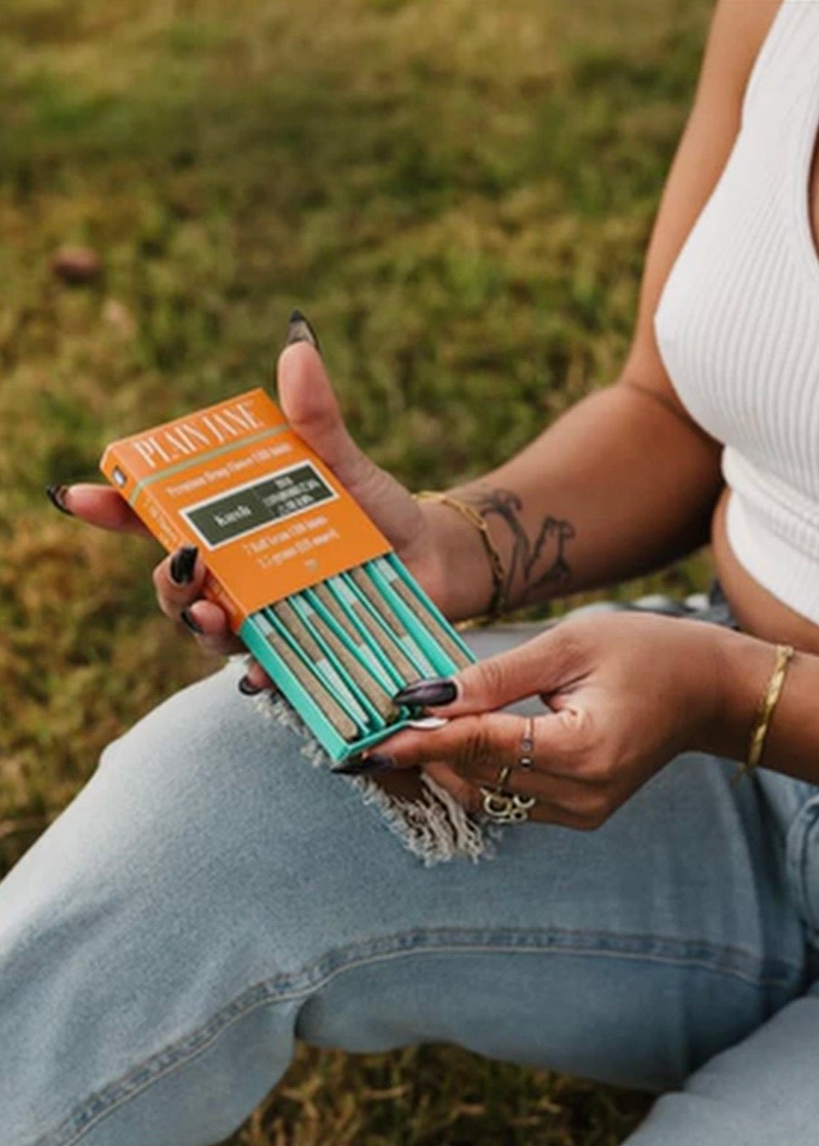 Person holding an orange Plain Jane package